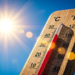 Symbolic image shows wooden thermometer against a blue sky and bright sun, reading about 40 degrees Celsius.