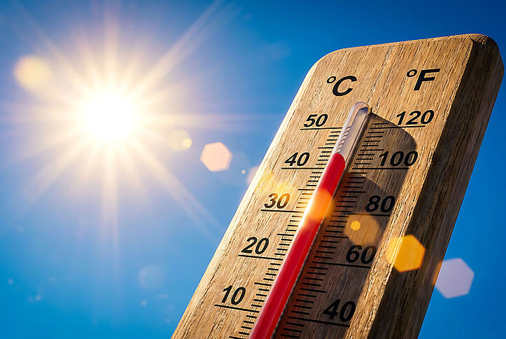 Symbolic image shows wooden thermometer against a blue sky and bright sun, reading about 40 degrees Celsius.