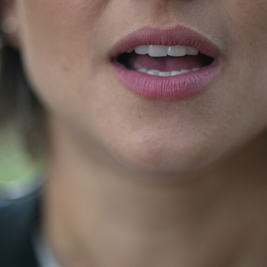 Image shows detail of mouth of talking woman