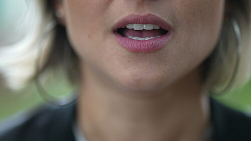 Bild zeigt Detailaufnahme des Mundes einer sprechenden Frau