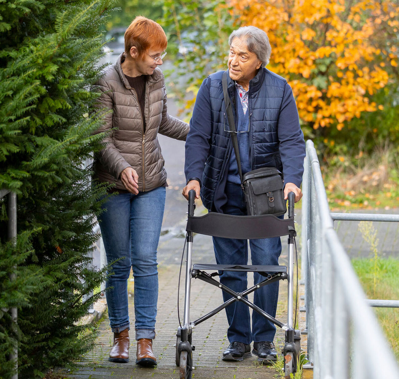 Picture shows a care worker with an elderly gentleman on a rollator.